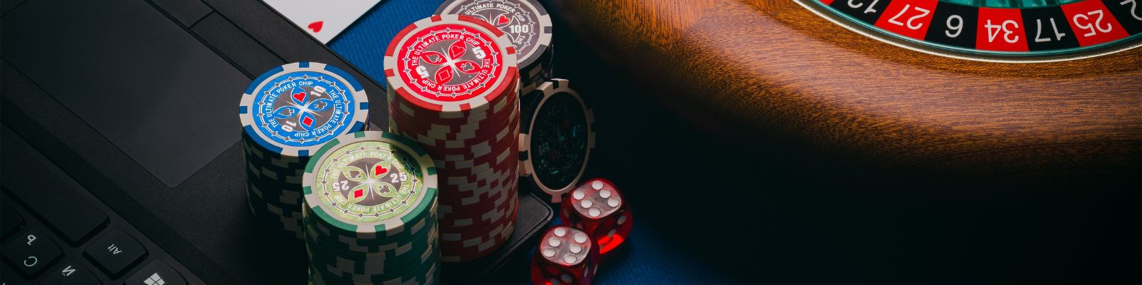 Fichas de poker ao lado de uma roleta sobre um notebook